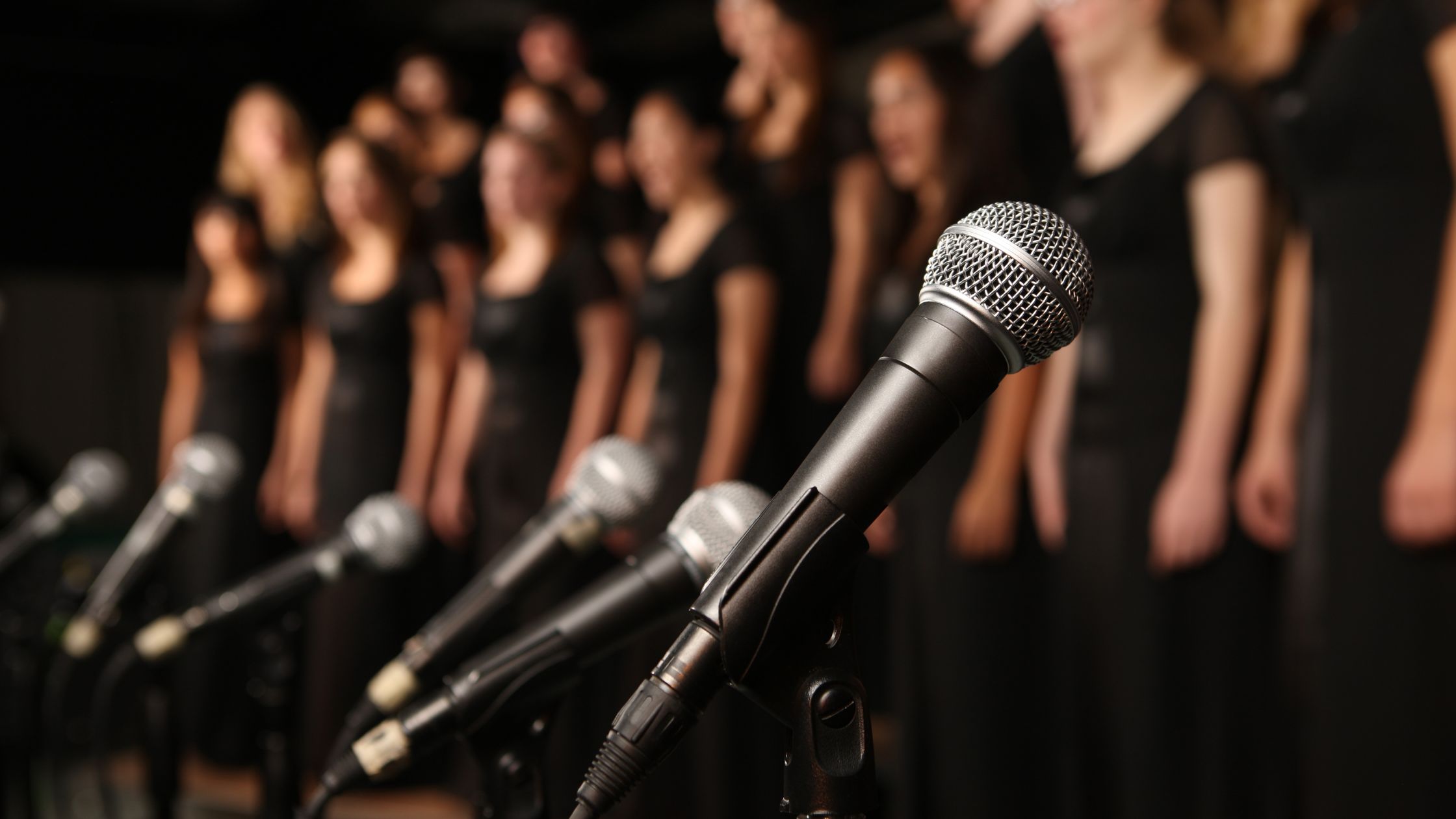 Choir performing with multiple microphones, showcasing harmony and group singing benefits.
