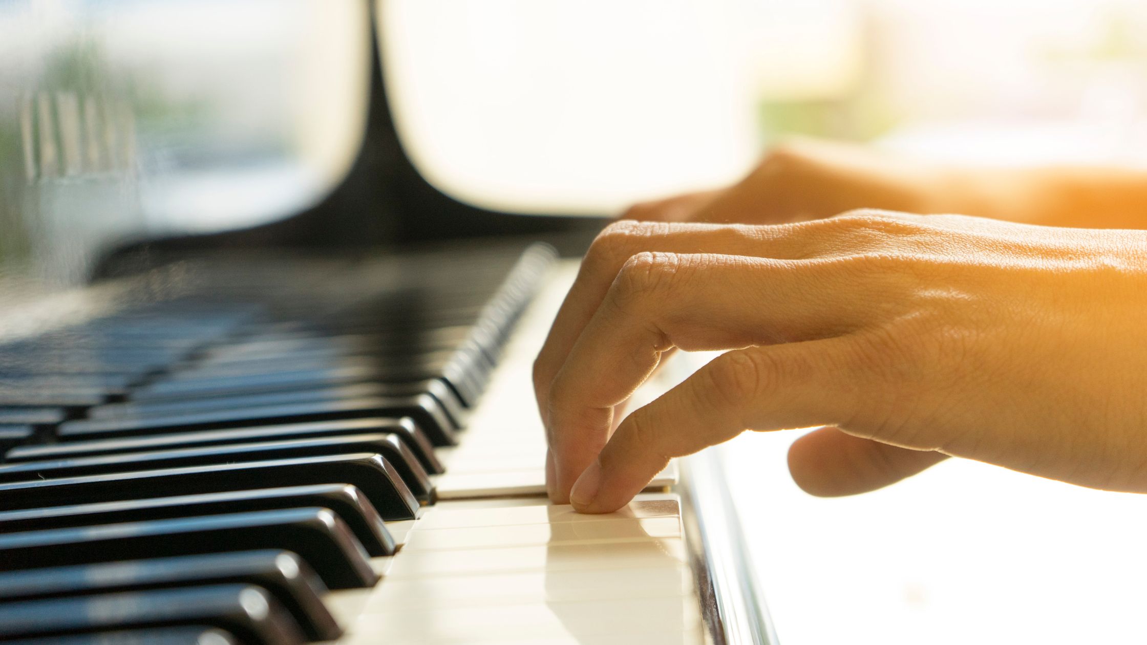 Close-up of hands playing piano keys, symbolizing emotional wellness and brain development.