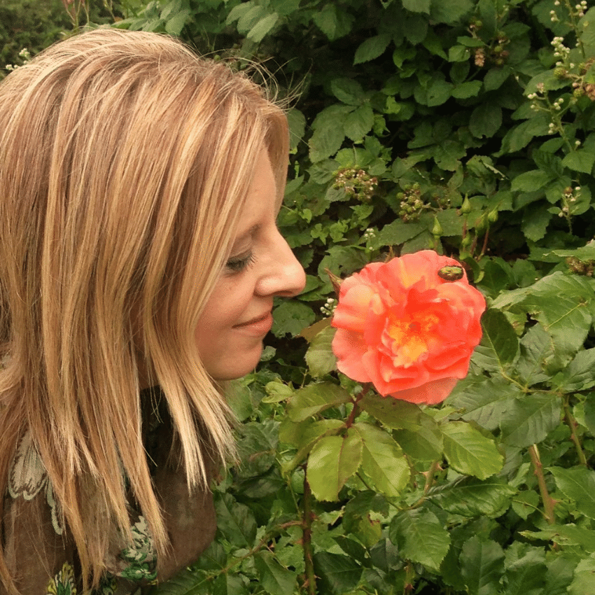 Music teacher Ana smelling an orange rose, embracing mindfulness and music education.