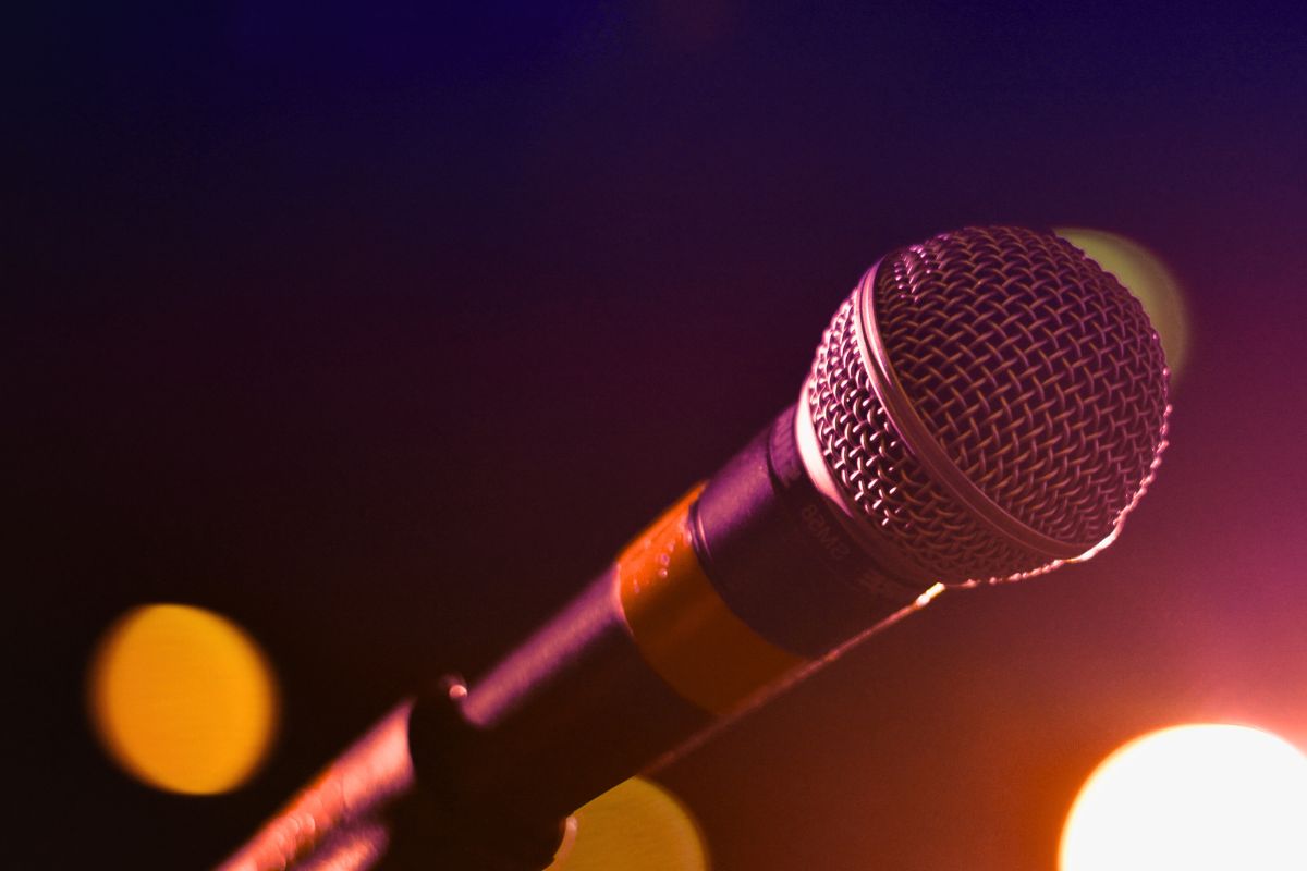 Microphone under stage lights, promoting free PDF guide for singing tips.